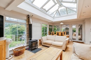 A spacious room with a large skylight, a sofa, a fireplace, and a television.