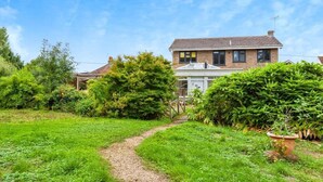 Una casa de dos pisos con un camino de jardín que lleva a la entrada.