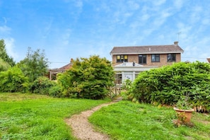 A two-story house with a garden path leading to the entrance.