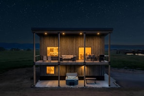 A two-story wooden cabin with a balcony, a hot tub, and a dining area. - Upper-Level Living, Stars, HotTub, Mtn Views, Pets (Driggs)