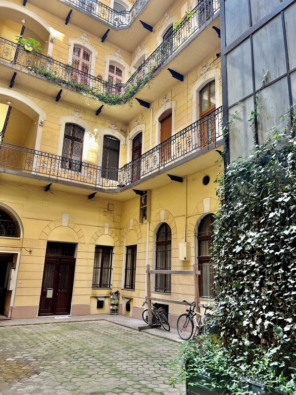 A multi-story building with balconies, a courtyard, and a bike parked outside.