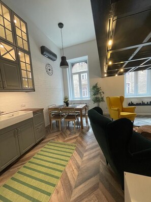 A modern kitchen with a dining area, a black hanging light fixture, and a large window. - Awesome Loft- King Street Budapest (Budapest)