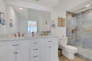 A modern bathroom with a marble vanity, a toilet, and a shower with a glass door. - Gulf-Front Bonita Beach, FL Condo -  Private Beach Access + Pool / Gulf views (Bonita Springs)