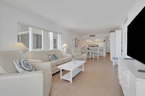 A modern living room with a sofa, coffee table, and a television. - Gulf-Front Bonita Beach, FL Condo -  Private Beach Access + Pool / Gulf views (Bonita Springs)