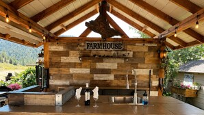 Un bar de estilo rústico en una casa de campo, con paredes de madera, una encimera de metal y tres taburetes de metal.