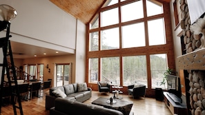 A spacious living area with a large window, a sofa, a coffee table, and a fireplace.