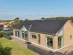 A modern house with a sloped roof, large windows, and a patio area. - 4 Star Holiday Home in Ebeltoft (Ebeltoft)
