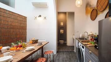 A compact kitchen with a washing machine, a dining area with a table set for two, and a small bathroom visible in the background.