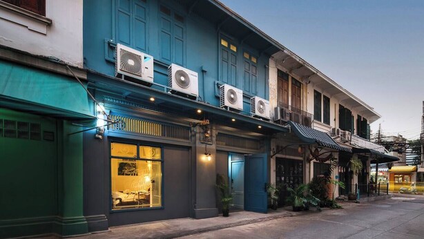 A two-story building with air conditioning units, a storefront with a glass door, and a staircase leading to the upper floor. - The Post and Barber · Cook In, Hang Out, Sleep Eight (Bang Rak)