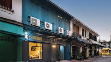 A two-story building with air conditioning units, a storefront with a glass door, and a staircase leading to the upper floor.