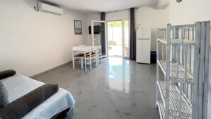 A room with a bed, a table with chairs, a refrigerator, and a window with a view. - One bedroom apartment with sea view (1) (Loviste)