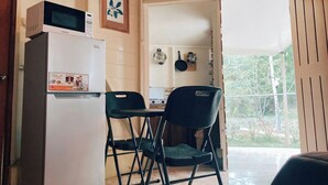 A compact kitchen with a refrigerator, microwave, and a small dining table with two chairs.