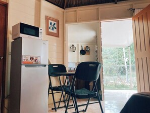 A compact kitchen with a refrigerator, microwave, and a small dining table with two chairs.