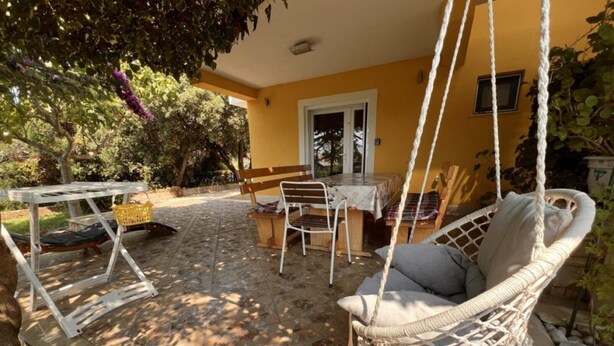 Un patio con una sedia a dondolo, un tavolo e una panca.