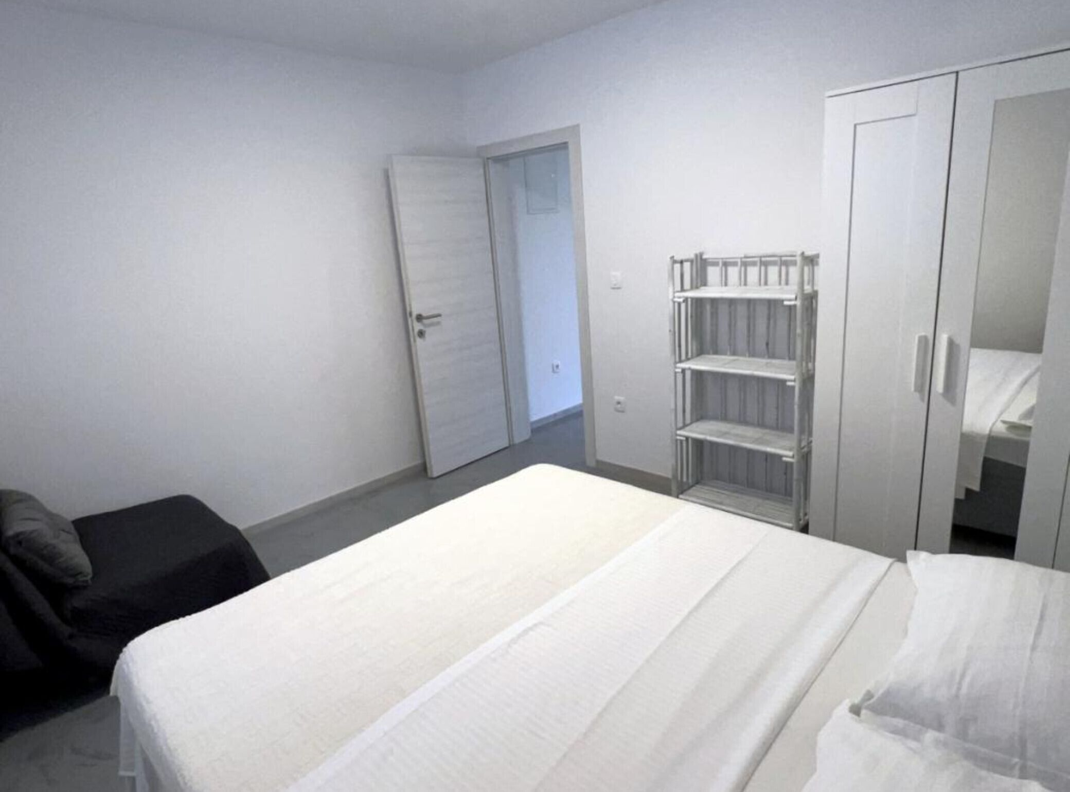 Et soveværelse med seng, garderobeskab og reol.