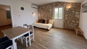 Une pièce avec un mur en pierre, un lit, une table avec des chaises et un appareil de climatisation.