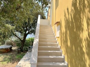 A staircase leading up to a building with a yellow exterior wall. - One bedroom apartment with sea view (3) (Loviste)