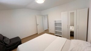 Une chambre à coucher comprenant un lit, une armoire, une étagère et une porte donnant sur une autre pièce.