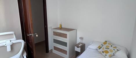 Ein Hotelzimmer mit Bett, Nachttisch, Schreibtisch und Stuhl sowie einem Deckenventilator.