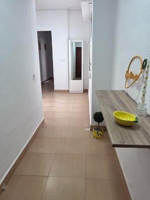 A hallway with a wooden floor, a white door, a small potted plant, and a yellow bowl on a wooden table. - Bright apartment in Ruzafa near the Roig Arena and CAC | Sleeps up to 7 (1 bathroom) (València)