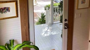 Eine Tür mit Fenster, eine weiße Veranda und Blick auf eine Straße mit Häusern.