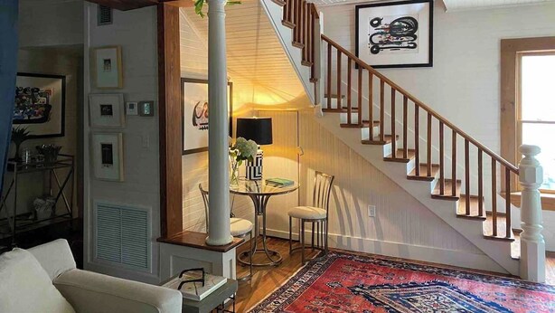 Ein Wohnzimmer mit Treppe, Essbereich und Blick auf eine Küche.