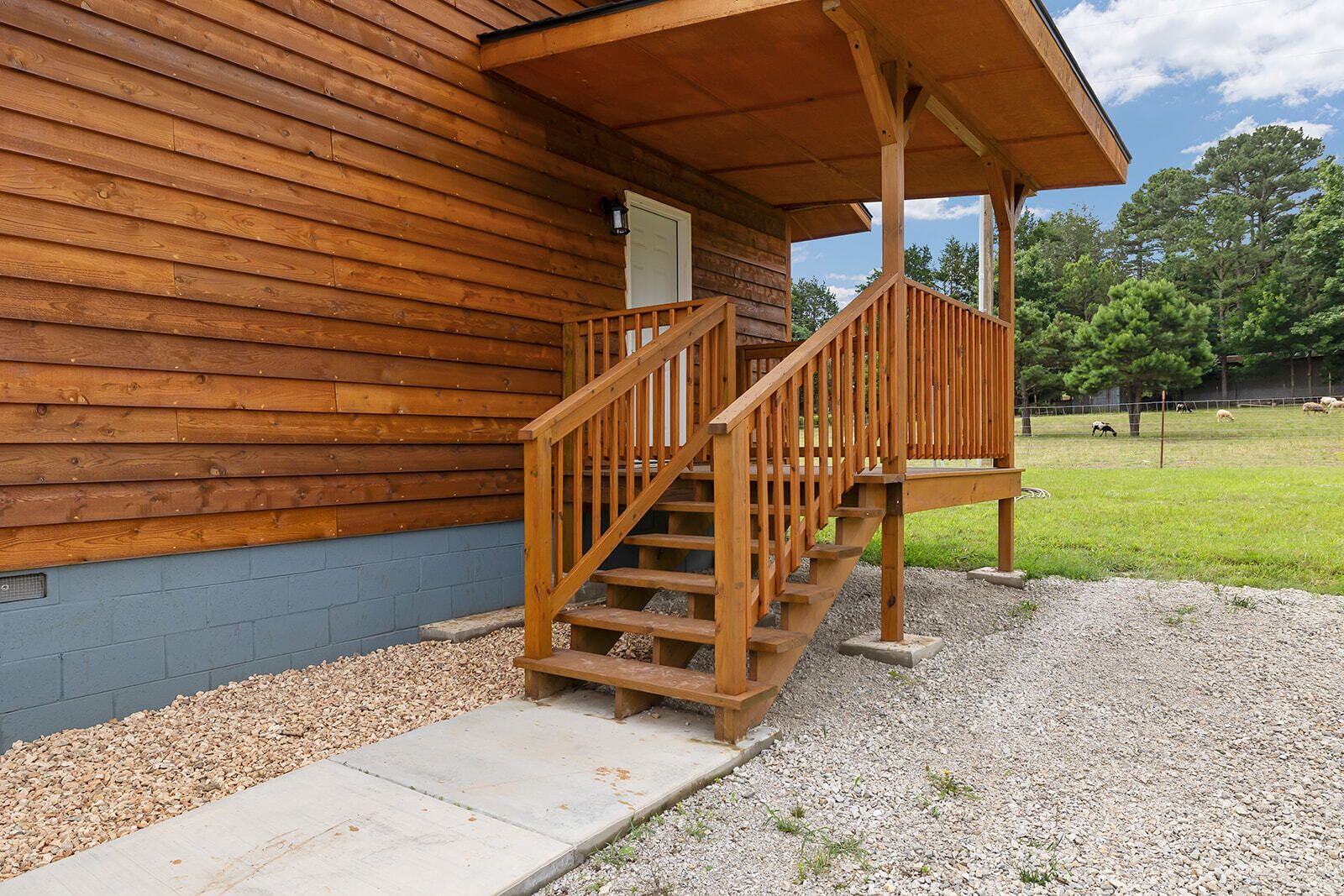 Una cabaña de madera con un porche y una escalera que lleva a una terraza.