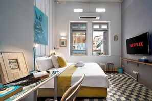 A hotel room with a bed, a desk with a computer, a TV displaying 'NETFLIX,' and a window with a view of the outside. - The Post and Jewelry · Two Best Sellers, One Booking (Bang Rak)