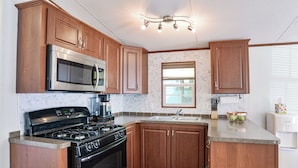 A kitchen with wooden cabinets, a stainless steel microwave, a gas stove, and a sink.