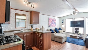 A compact kitchen with a gas stove, wooden cabinets, and a built-in sink.