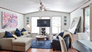 A living room with a ceiling fan, a sofa, a coffee table, and a TV.