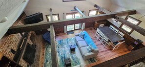 Ein Loft-Zimmer mit Schlafgalerie, einer Couch, einem Esstisch und einem Fernseher.