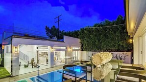 A modern house with a glass pool, a staircase, and a well-lit interior. - Stunning Indoor/Outdoor Space w/H Hills View, Pool - Casa Bonita LA (Los Angeles)