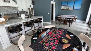 A modern kitchen with a built-in stove, bar stools, and a roulette table. - Stunning Indoor/Outdoor Space w/H Hills View, Pool - Casa Bonita LA (Los Angeles)