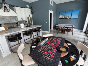 Eine moderne Küche mit Einbauherd, Barhocker und einem Roulette-Tisch.