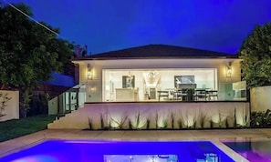 Una casa moderna con piscina, un patio cubierto e interiores bien iluminados.