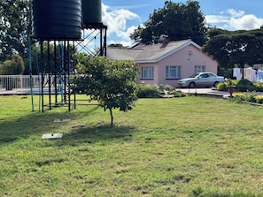 Un barrio residencial con una casa rosa, un coche aparcado delante y una estructura de depósito de agua.