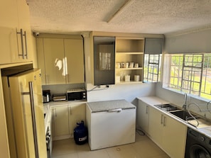 Cocina compacta equipada con microondas, estufa a gas, pileta y heladera pequeña.