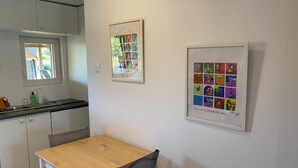 A kitchen with white cabinets, a window, and a framed pop art print on the wall. - Welcome to the Duchy of Uzes, in the charming village of Ste Eulalie. (Garrigues-Sainte-Eulalie)