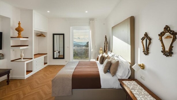 Un dormitorio con cama, mesita de noche y vistas al exterior.