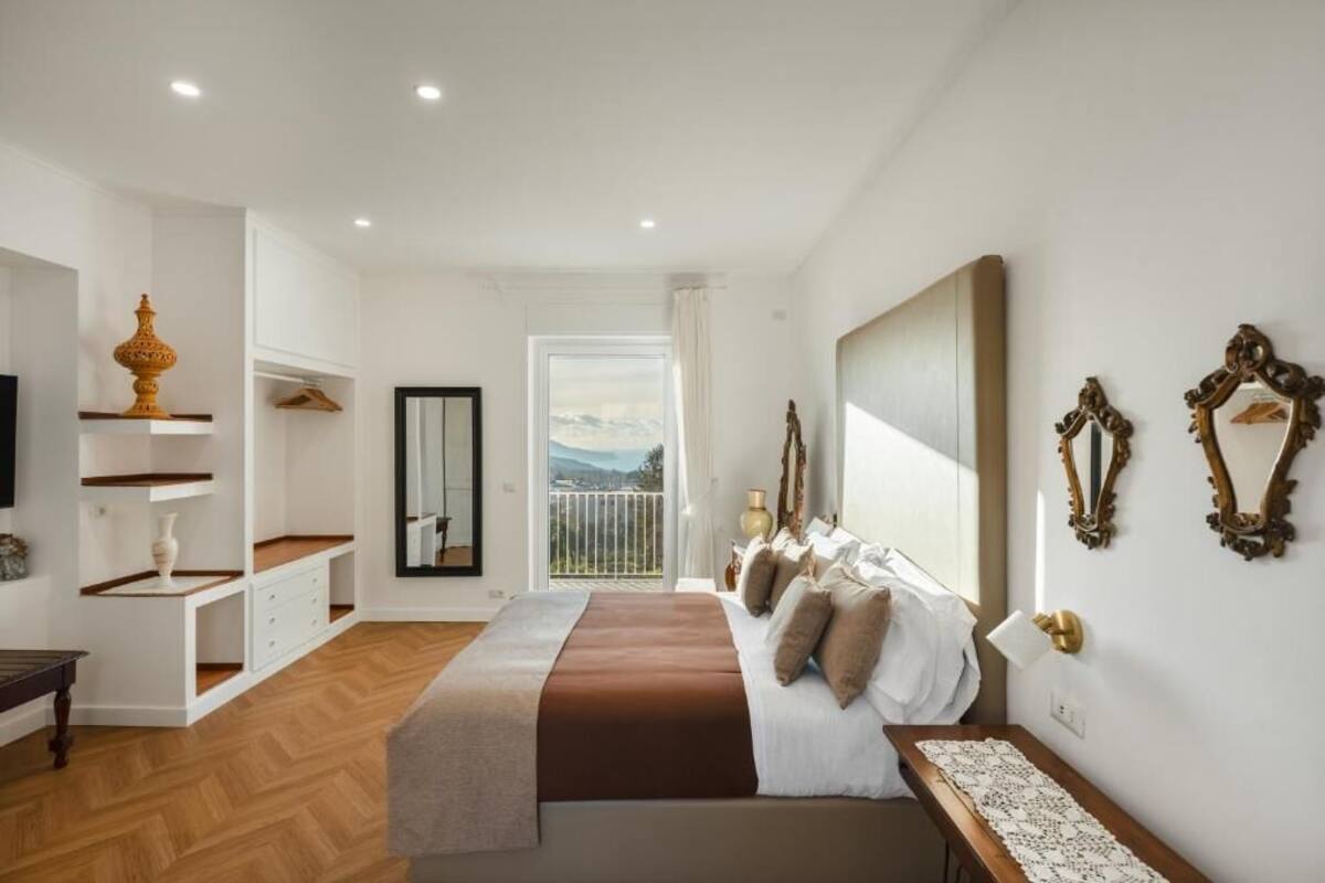 A bedroom with a bed, bedside table, and a view of the outdoors.
