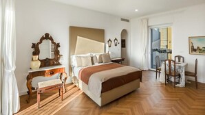 Un dormitorio con cama, cómoda, espejo, banca, mesa y sillas.