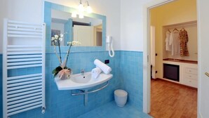 Un baño con lavamanos blanco, azulejos azules, un perchero, un espejo y una zona de ducha.