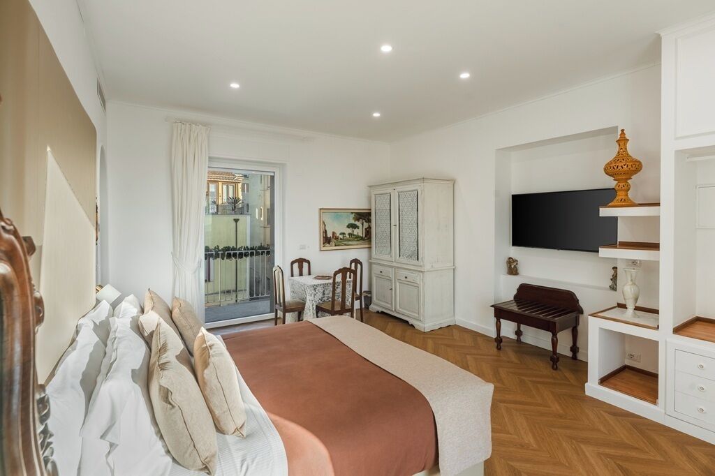 A bedroom with a bed, a desk, a chair, a television, and a cabinet.