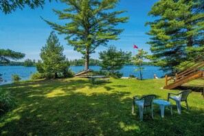 Un área de picnic junto al lago, con muelle de madera, mesa y sillas.