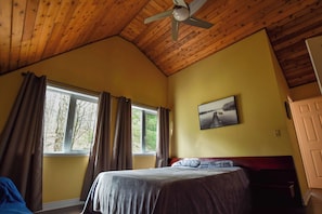 A room with a bed, a ceiling fan, a window with curtains, and a painting on the wall. - Rosseau Cathedral Grove (Rosseau)