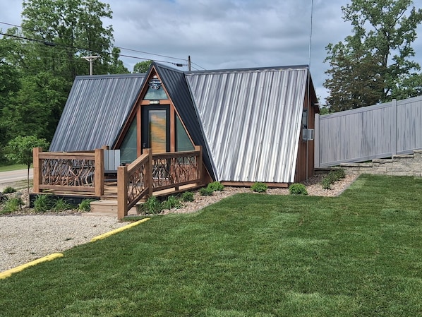 A modern building with a sloped roof, a wooden deck, and a fenced area.