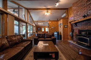 Ein gemütliches Blockhaus-Interieur mit einer Ledersofa, einem Holztisch, einem Kamin und großen Fenstern.