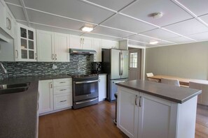 Una cocina moderna con gabinetes blancos, estufa de acero inoxidable y horno empotrado.
