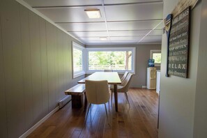 Comedor con mesa, sillas, dispensador de agua y vista al exterior.